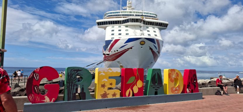 Colourful "Grenada" sign in foreground with a cruise ship docked in the background.