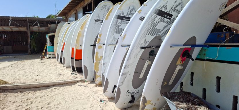 Row of small boats lined up on a sandy shore, leaning against each other.