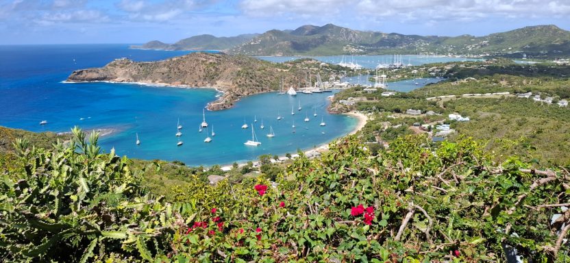 Scenic coastal view with vibrant blue waters, boats, and lush greenery.