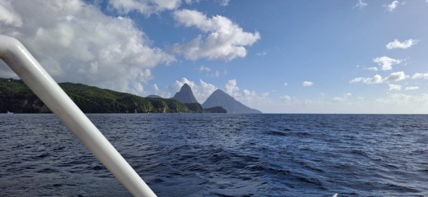 View of two volcanic peaks rising from the sea under a partly cloudy sky.