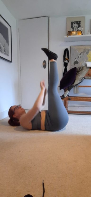 Jodie performing a leg exercise while lying on a carpeted floor.