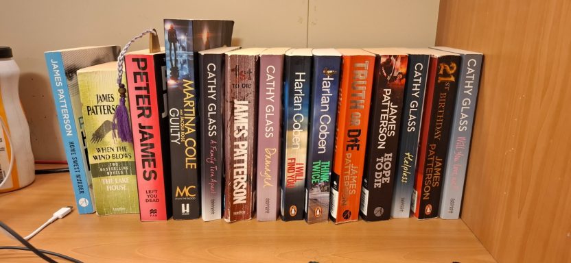 A row of various books on a wooden shelf.