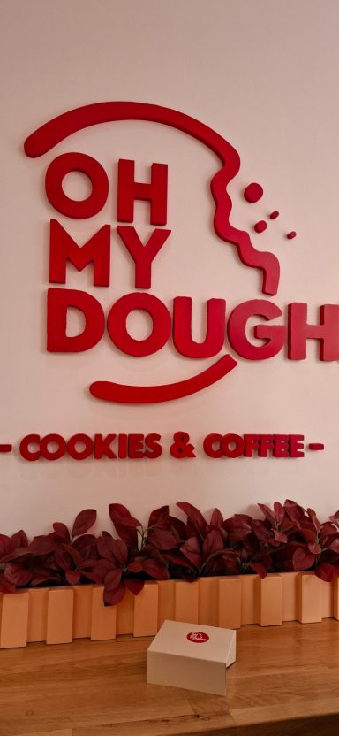 Red wall sign reading "Oh My Dough - Cookies & Coffee".