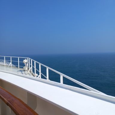 View from a ship's deck overlooking calm blue sea and clear sky.